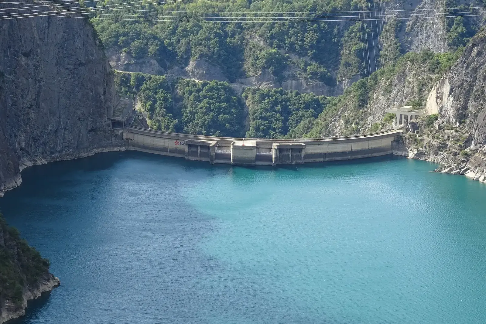 Le barrage-voûte de Monteynard au fond d'une gorge boisée, retenant un lac turquoise