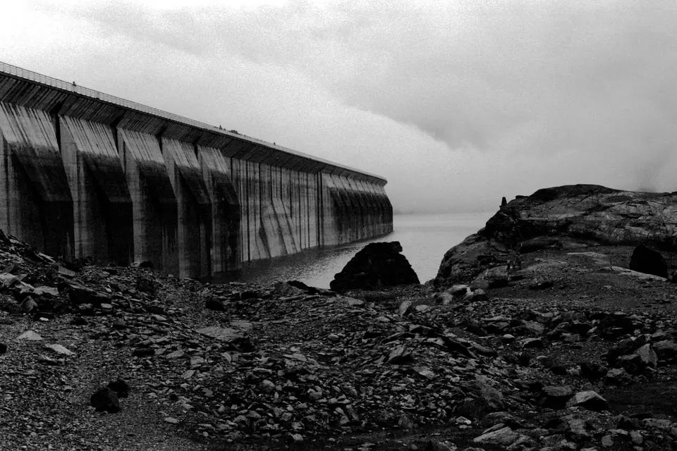 Photographie en noir et blanc du barrage à contreforts de Roselend et de son lac sous la brume