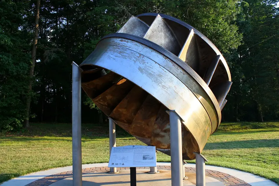 Roue de turbine Francis en acier exposée sur un support métallique dans un parc