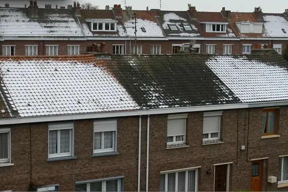 Toits de maisons mitoyennes en brique : la neige a fondu sur un pan de toiture et tient sur les voisins